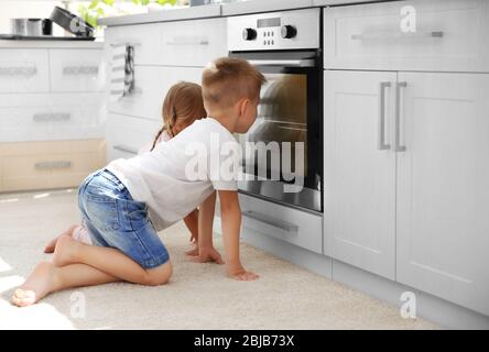 Kids playing in kitchen and waiting for preparation of biscuits in oven Stock Photo