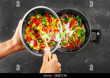 Woman putting chopped bell pepper with onion in saucepan, top view Stock Photo