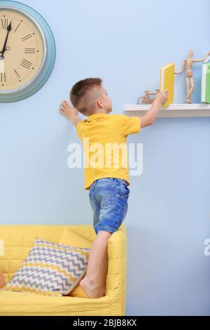 Cute boy taking book from shelf Stock Photo