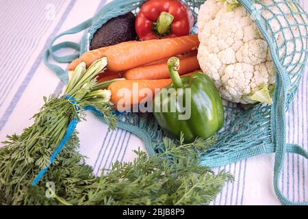 Close up of fresh produce in eco bag on kitchen table,reusable, sustainable, eco friendly, no plastic concept. Various vegetables: peppers, carrot, ca Stock Photo