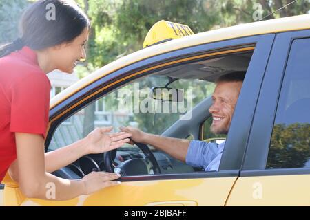 Beautiful woman talking with taxi driver through opened car window Stock Photo
