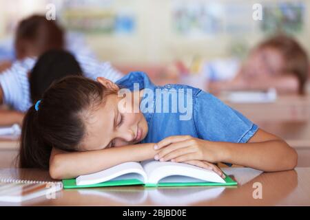 Tired schoolgirl in classroom on lesson Stock Photo