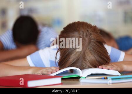 Tired schoolgirl in classroom on lesson Stock Photo