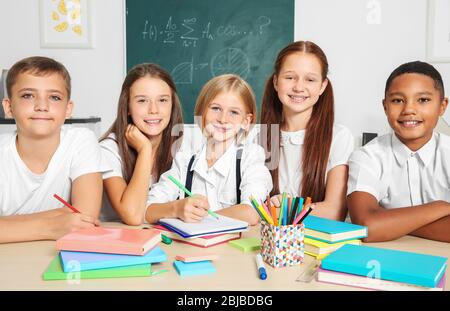 Schoolchildren drawing while sitting at table in classroom Stock Photo