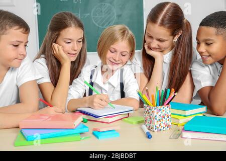 Schoolchildren drawing while sitting at table in classroom Stock Photo