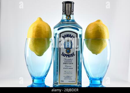 Bottle of Bombay Sapphire gin with two goblets and lemons white background Stock Photo