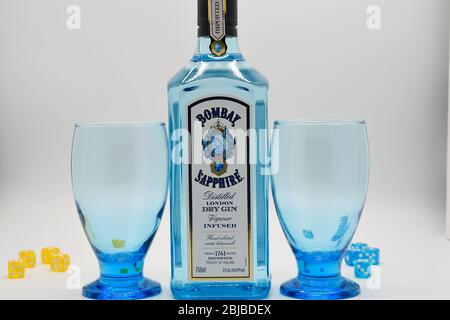 Bottle of Bombay Sapphire gin with goblets and blue and yellow dice white background Stock Photo