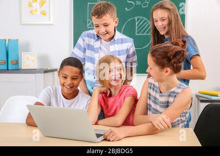 Schoolchildren with laptop in classroom Stock Photo