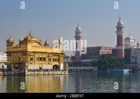 Harmandir Sahib rises out of the holy Pool of Nectar with towers of Guru ka Langar in the rear, the world's largest community kitchen, Amritsar, India Stock Photo