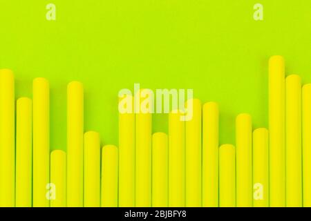 Drinking straws on bright neon green background Stock Photo