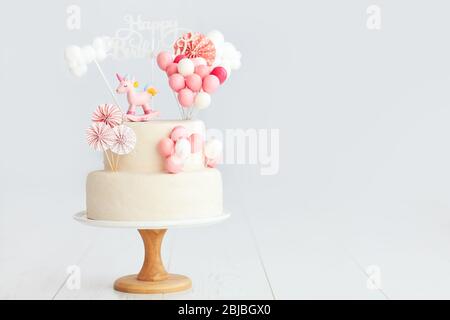 baby girl birthday cake with unicorn and balloons Stock Photo