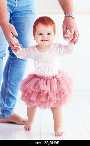 dad holds adorable little girl, helping her to make the first steps Stock Photo