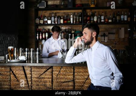 Man in white shirt speaking by cellphone near wooden bar counter Stock Photo