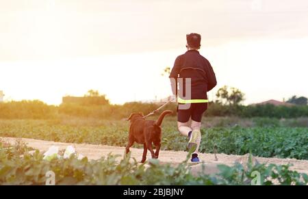 Sportsman running with his dog during phase 1 de- escalation of Coronavirus or Covid-19 in Spain. It is allowed running once a week Stock Photo