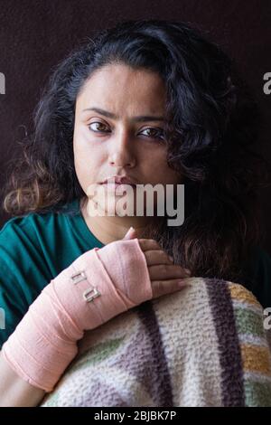 Indian woman with her broken wrist recovering in hospital bed looking at camera Stock Photo