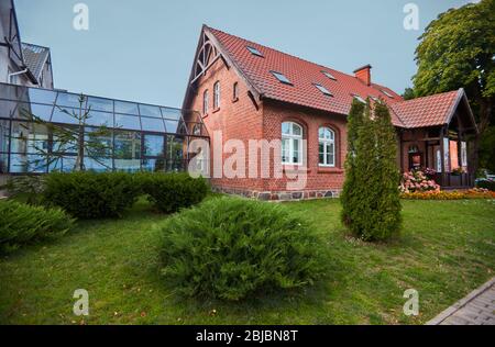 JUODKRANTE, LITHUANIA - August 18, 2019: Beautiful street with old Lithuanian traditional brick house. Fishermen's village on Baltic sea, popular tour Stock Photo