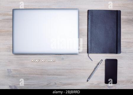 minimalist flat lay of a computer, smart phone, notebook and pen on a wooden table with the message "work at home", concept of online entrepreneur and Stock Photo