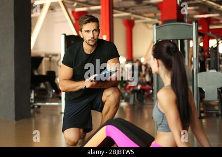 Young athletic woman doing exercises with trainer in gym Stock Photo