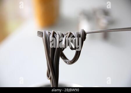 Black pasta on fork in kitchen Stock Photo
