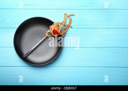 Fork with pasta and tomato on black plate Stock Photo