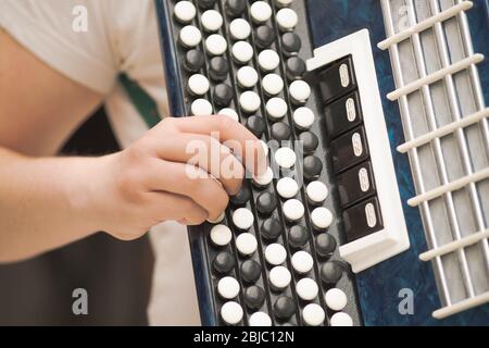 Accordion in the hands of a musician, close-up view. Street music image, busker playing a melodeon Stock Photo