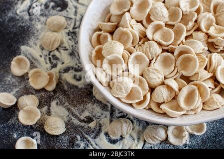 Fresh raw apulian pasta orecchiette made from whole wheat flour on a dark table close up Stock Photo
