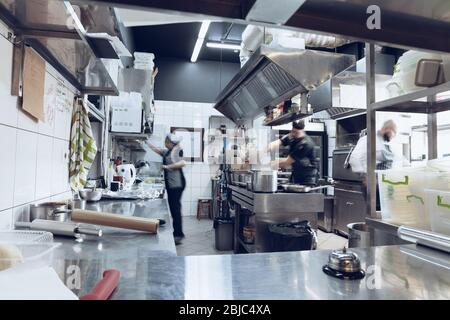 Behind the scenes of brands. The chef cooking in a professional kitchen of a restaurant meal for client or delivery. Open business from the inside. Meals during the quarantine. Hurrying up, motion. Stock Photo