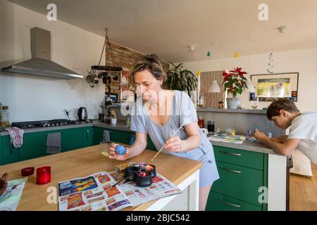 mother and son colouring Easter egg at home in the kitchen Stock Photo