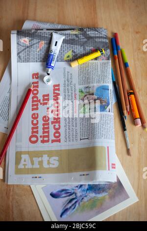 Arts & Culture News concept during Coronavirus lockdown. UK, April 2020. Arts in the News with art materials & newspaper on desk. Stock Photo