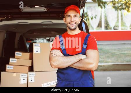 Delivery man standing near car Stock Photo