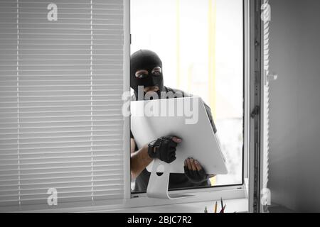 Thief stealing monitor from office Stock Photo