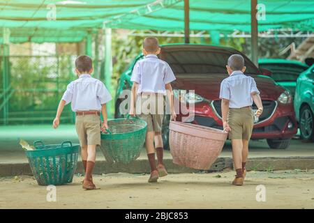 Male Students help to remove rubbish from the classroom to pile waste Stock Photo