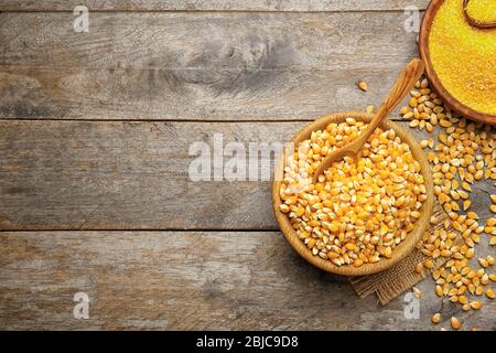 Corn seeds and groats in bowls on wooden table Stock Photo