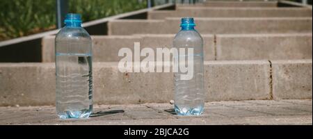 Two plastic bottles of clean drinking water on the road, source of life. Banner. Stock Photo