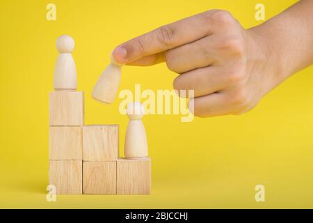 The hand is picking or select wood figure on the wooden  Stacked in human resource management concepts Teamwork.Success Leadership,Business Progress a Stock Photo
