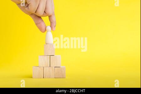 The hand is picking or select wood figure on the wooden  Stacked in human resource management concepts Teamwork.Success Leadership,Business Progress a Stock Photo