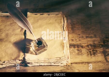 Feather pen with inkwell and stack of papers on wooden table closeup Stock Photo
