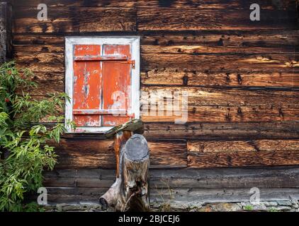 Closed window with vintage orange shutters on an old Swiss farm house Stock Photo