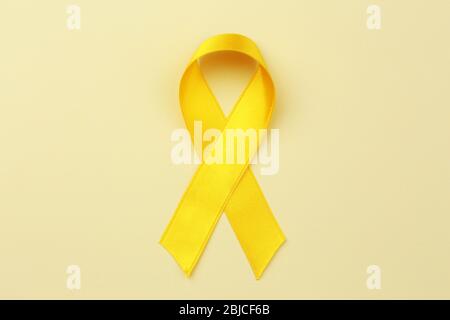 Yellow ribbon on color background.  Suicide, endometriosis, bone cancer concept Stock Photo