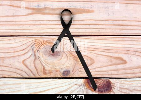 Black ribbon on wooden background. Melanoma and mourning concept Stock Photo