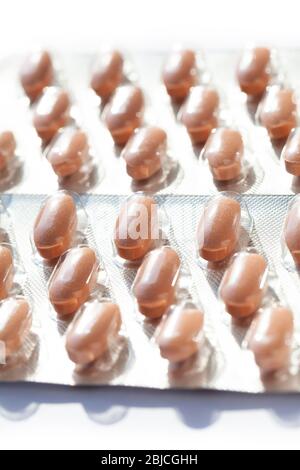 Multiple capsules in blister packs, packages closeup. Pills, orange tablets in simple plastic packaging container seen from up close, pharmacy concept Stock Photo