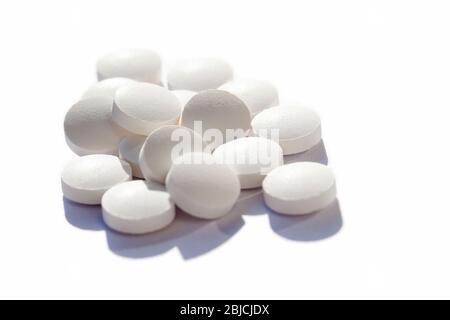 Many generic small round white pills, lots of little tablets on white background closeup. Simple group of little pills, medicine, medication and drugs Stock Photo