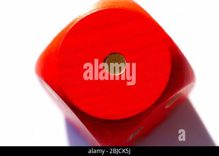 Simple red game dice showing one. Number 1 on a big wooden playing dice on white background, macro, extreme closeup. Low score, lost game, bad luck Stock Photo