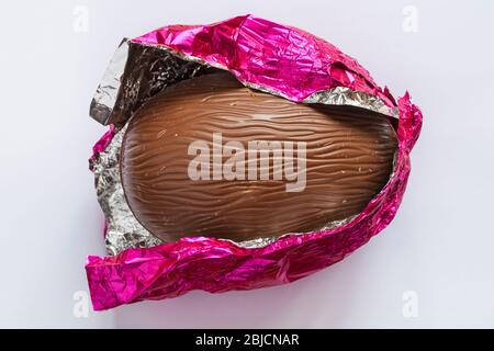 unwrapped Milk chocolate Easter egg in pink silver foil isolated on white background Stock Photo