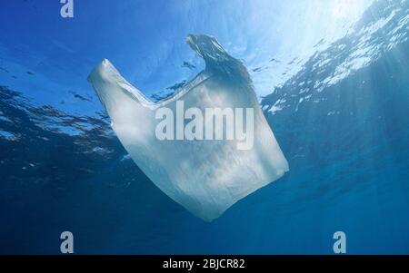 Plastic pollution underwater in the sea, a white plastic bag below water surface Stock Photo