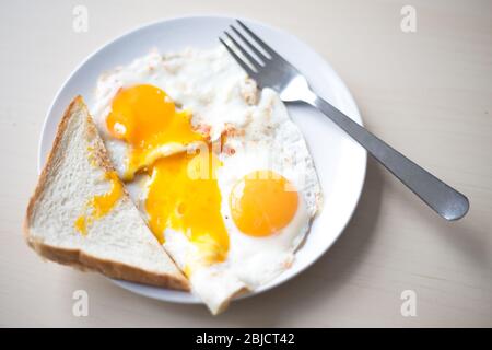 Two fried eggs with orange yolks, white toast in the morning for breakfast. Stock Photo