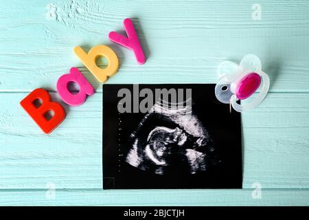 Ultrasound photo and pacifier on blue wooden background Stock Photo