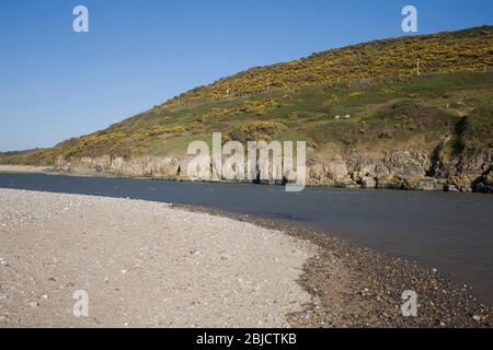 Mouth of the Ogmore river and the end of Newton beach with the B4524 road clinging to the hillside Stock Photo