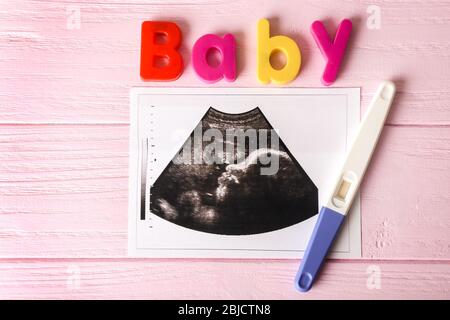 Ultrasound photo and pregnancy test on wooden background Stock Photo