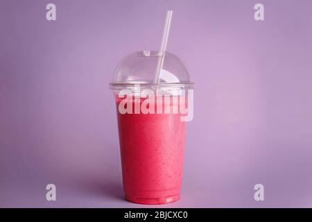 Delicious strawberry milkshake in plastic cup on purple background Stock Photo